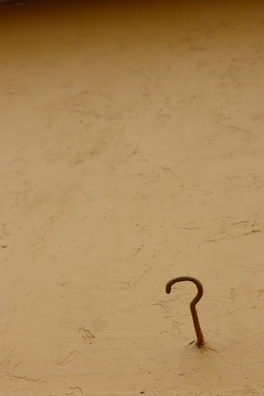 A hook is mounted on a cream-colored wall.