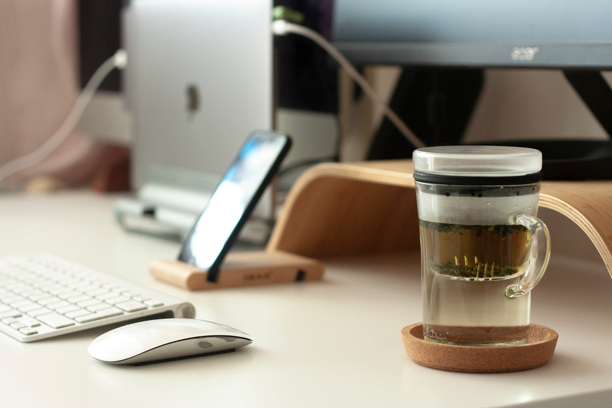 clear glass mug beside Apple Magic Mouse