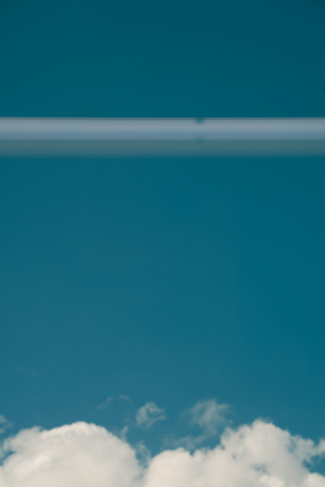 a plane flying through a blue sky with white clouds