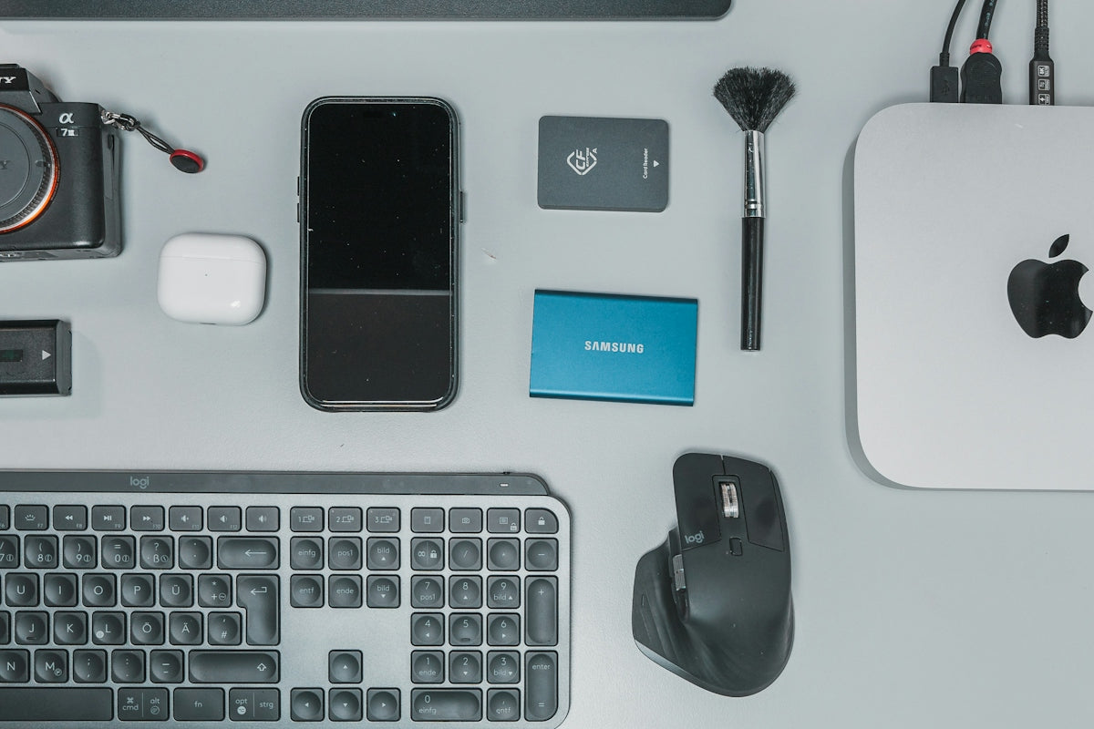a desk with a keyboard, mouse, cell phone and other items