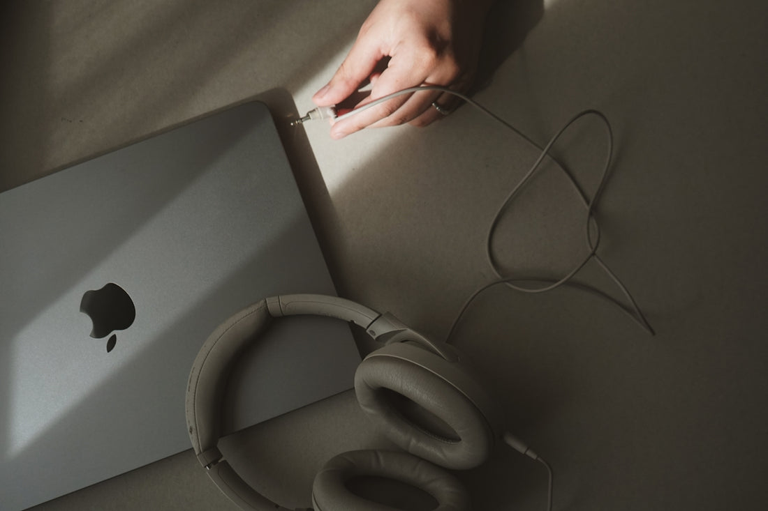 A person holding a laptop computer next to a pair of headphones
