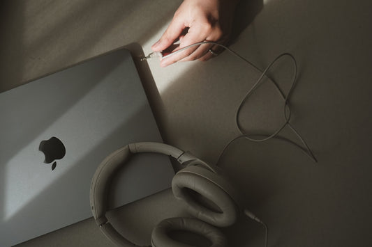 A person holding a laptop computer next to a pair of headphones