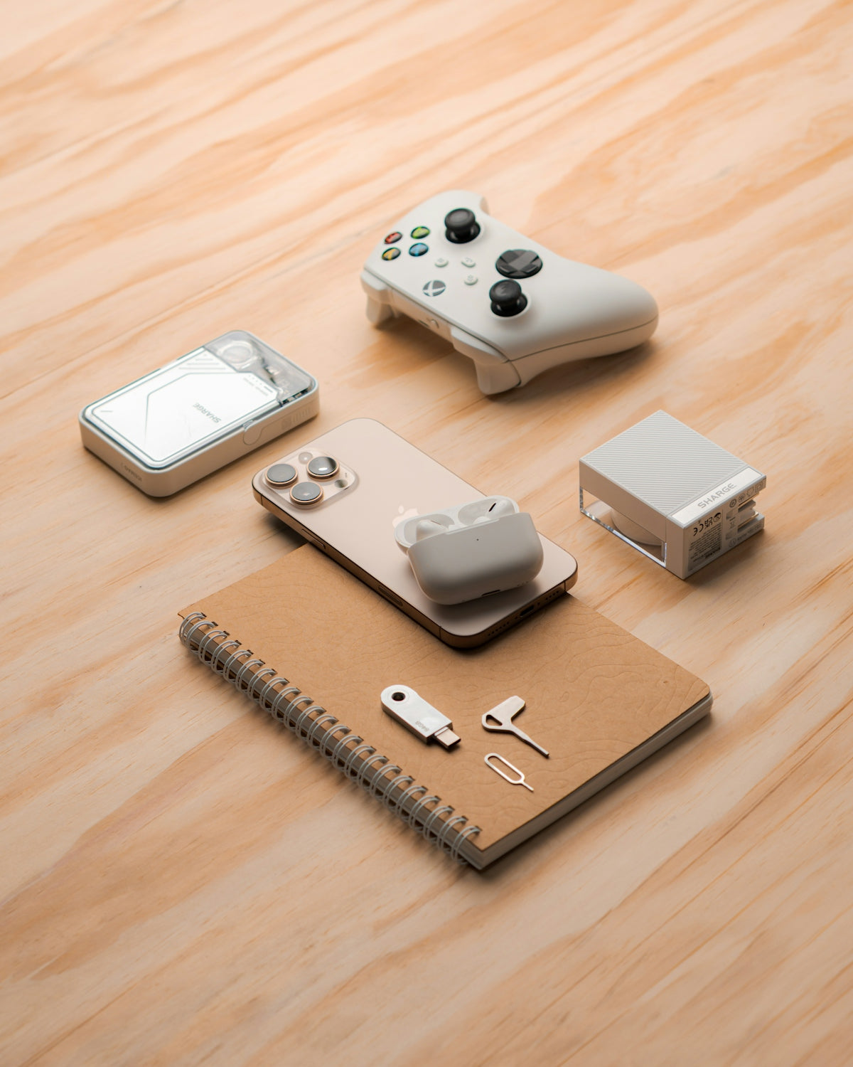 Gaming controller, smartphone, and accessories arranged on wooden surface.